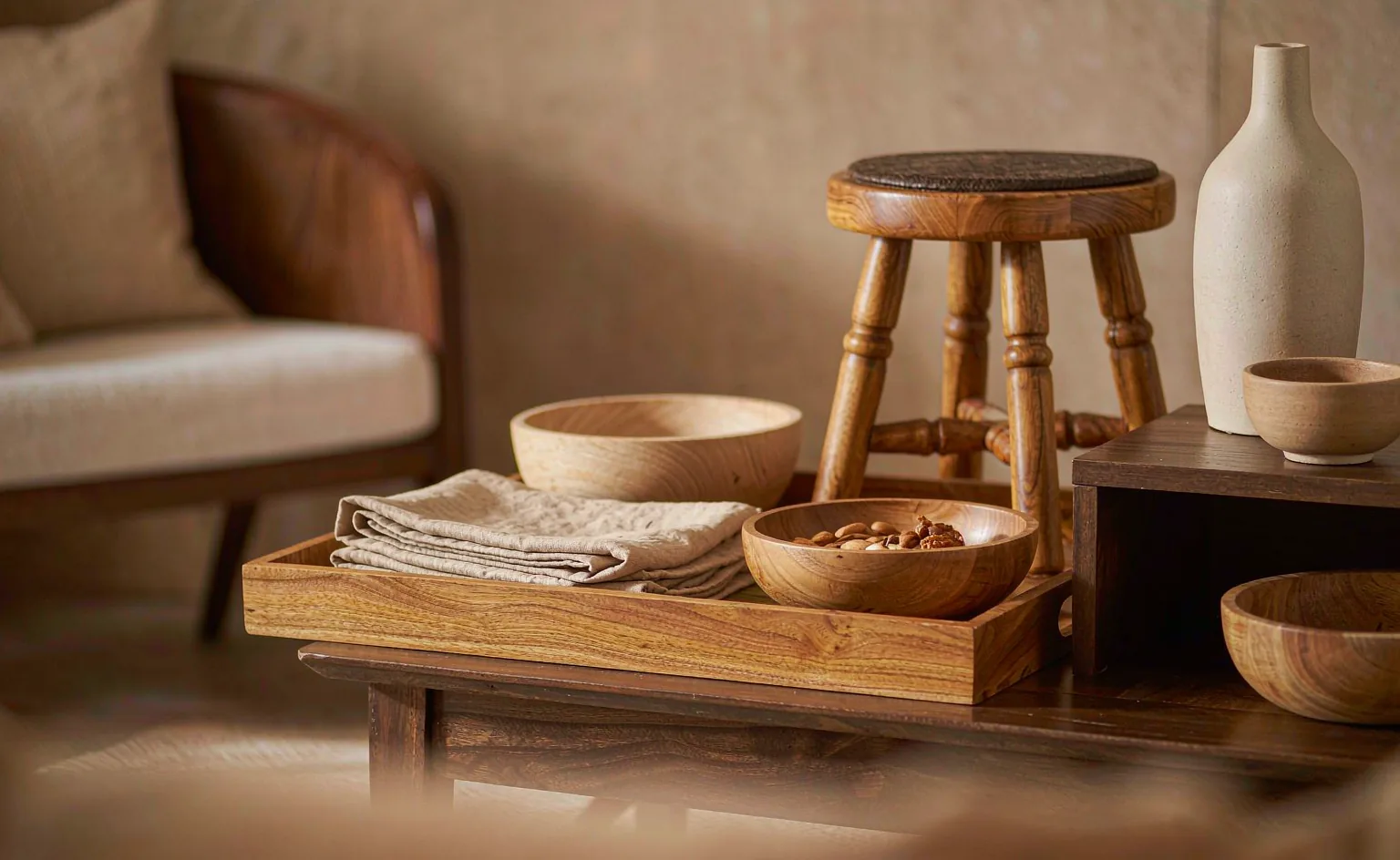 Teak serving tray, turned bowls and a stool styled in a warm living room